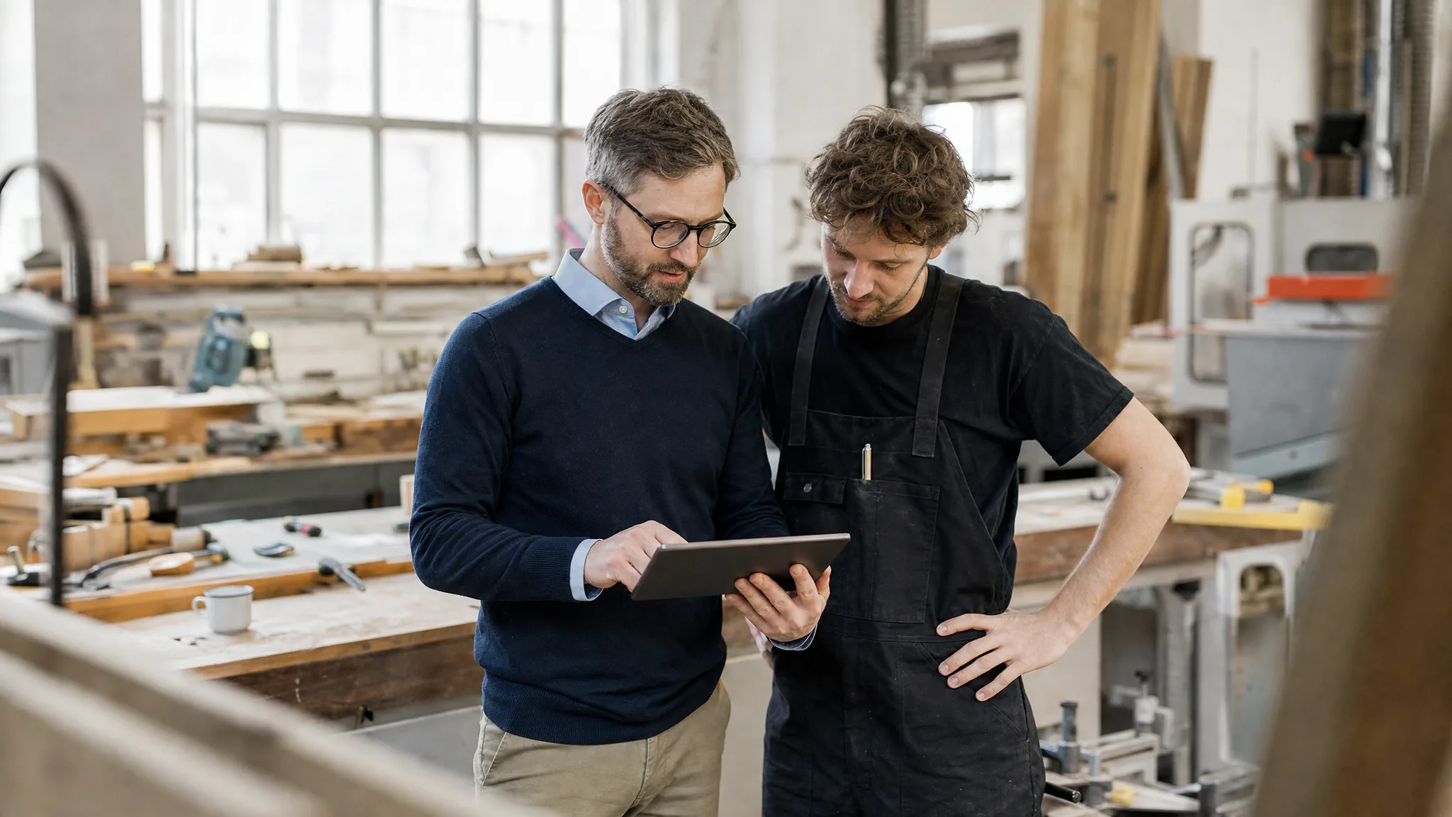Un conseiller et un artisan regardent une tablette ensemble dans un atelier en Alsace